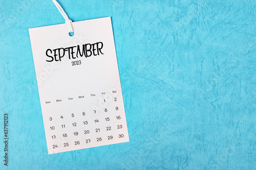 The 2023 September calendar page hanged on white rope  on blue background.