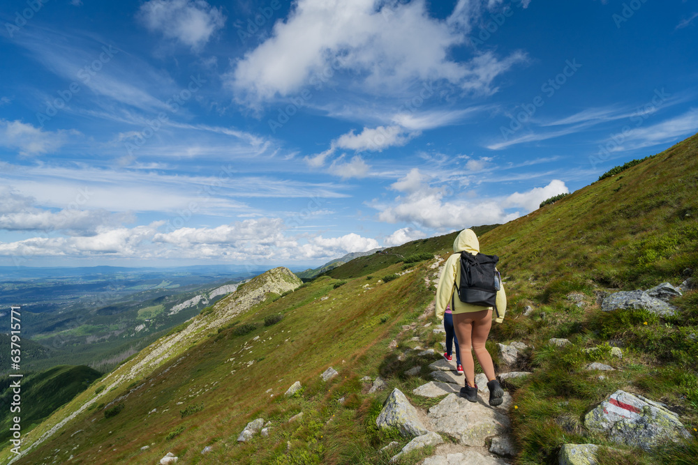 People go hiking in the Tatra Mountains in Poland on a summer day.