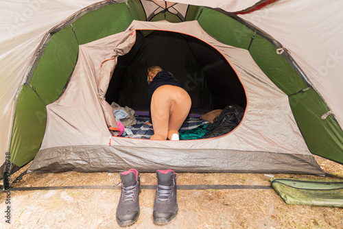 The girl climbs into a tent set in nature, rear view. photo