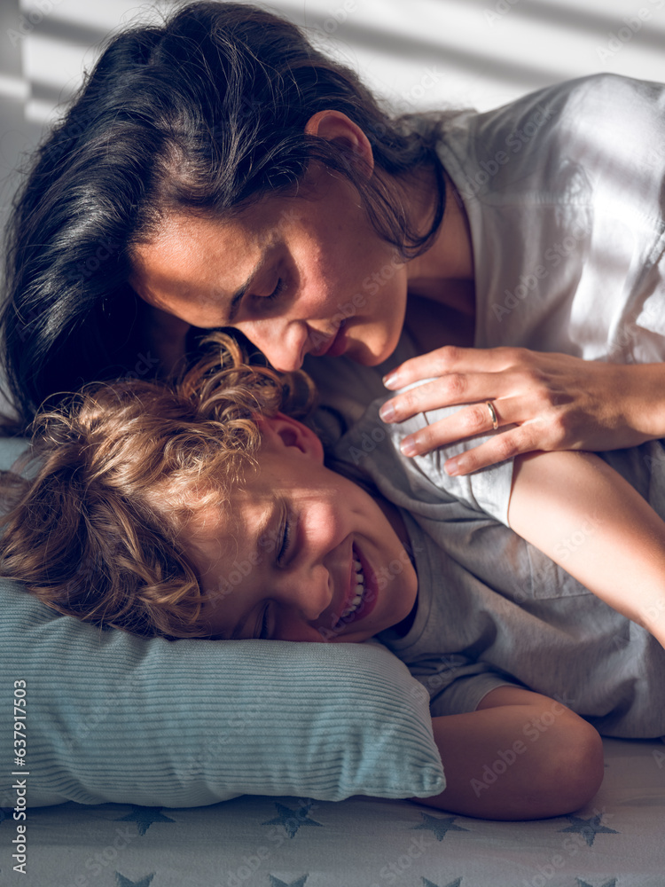 Cheerful boy resting on bed with mother Cheerful boy resting on bed with mother