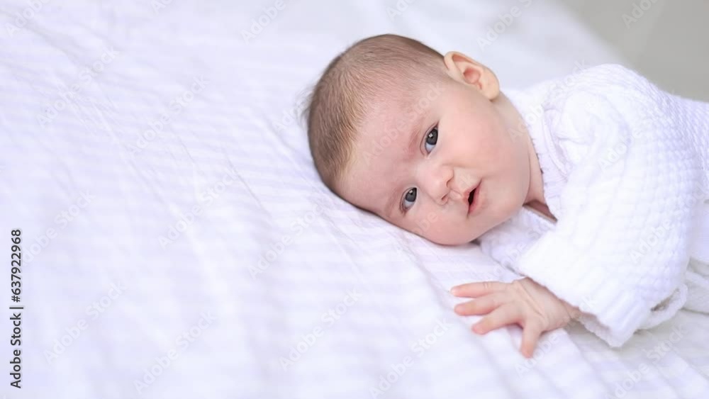 portrait of a newborn baby in a crib in a white warm jumpsuit on a white insulated cotton bed, cute baby close-up portrait of a newborn baby in a crib in a white warm jumpsuit on a white insulated cotton bed, cute baby close-up
