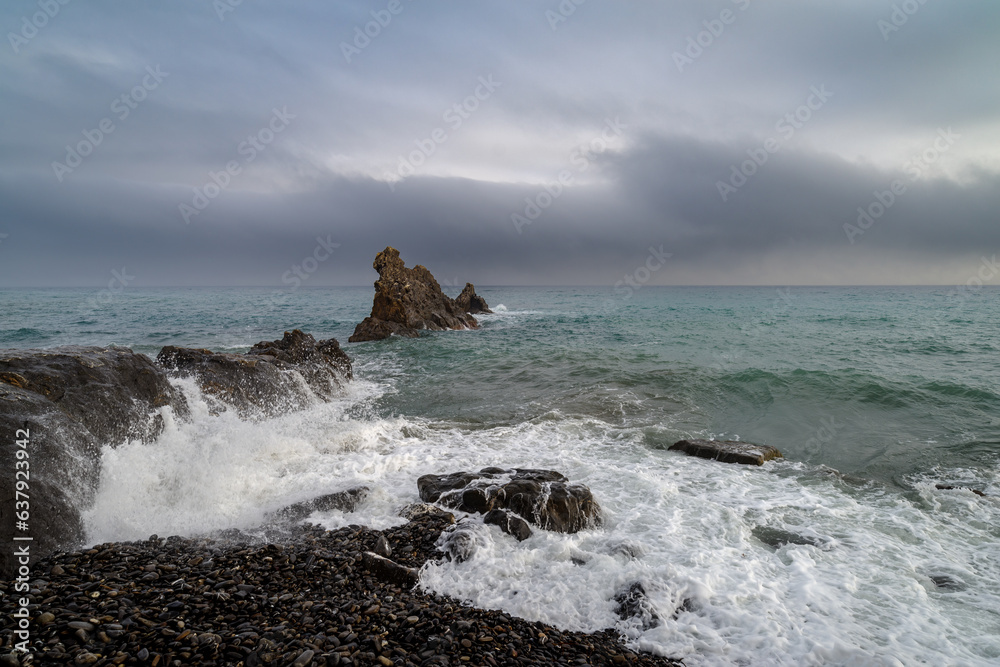Seascape image of white waves rushing up the rocky beach