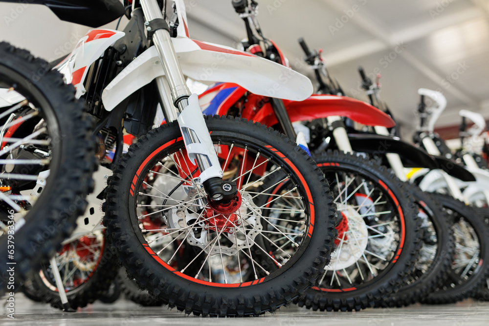 There are many colorful motorcycles for sale in the exhibition hall. Wheels close-up.