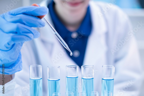Professional scientist chemist technician analysis research experiment virus blue liquid pipette glass test tube equipment in hospital laboratory, woman doctor white lab coat medical research develop
