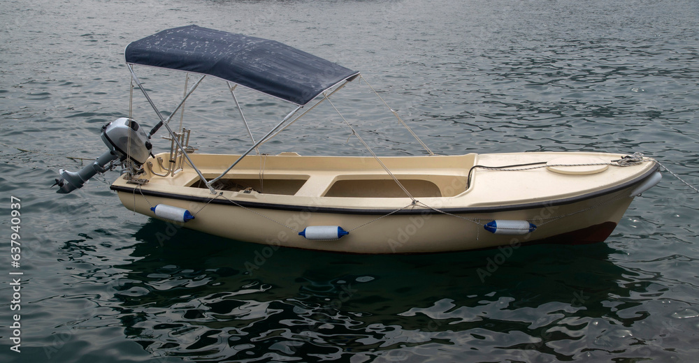 Naklejka premium A small fiberglass boat with motor and awning in water in Montenegro