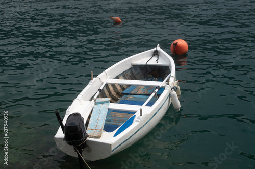 Small wooden boat with motor tied to a buoy in water in Montenegro, Europe