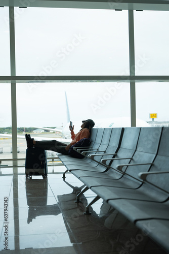 Woman checks her mobile phone while waiting for her flight at the airport.