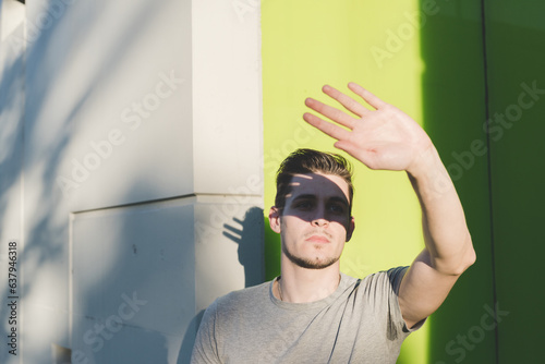 Obraz na plátně Man hiding sun with hand posing outdoors