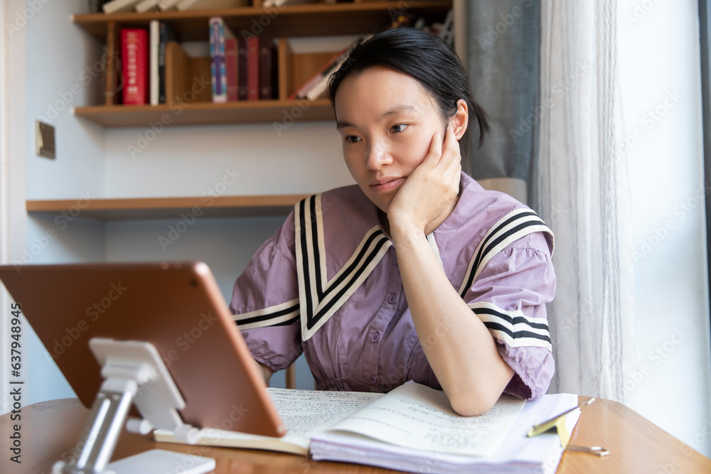 A young Chinese woman is learning on a tablet at home A young Chinese woman is learning on a tablet at home