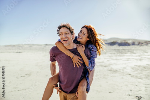 Middle aged caucasian couple walking and having fun on a beach during their vacations