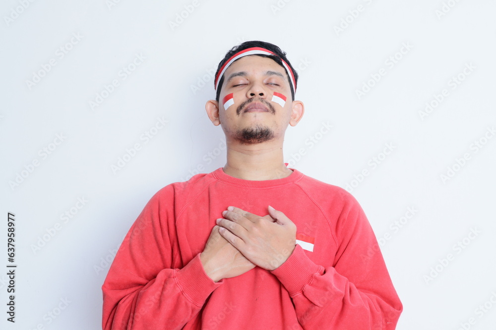Naklejka premium Indonesian man with hand on chest showing proud gesture, celebrating Indonesia independence day.