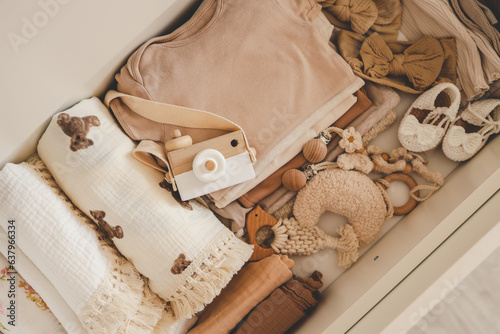 Flatlay aesthetic Scandinavian newborn baby clothes, baby care accessories, toys stacks in storage shelf. Trendy elegant neutral pastel colour infant fashion set. Top view