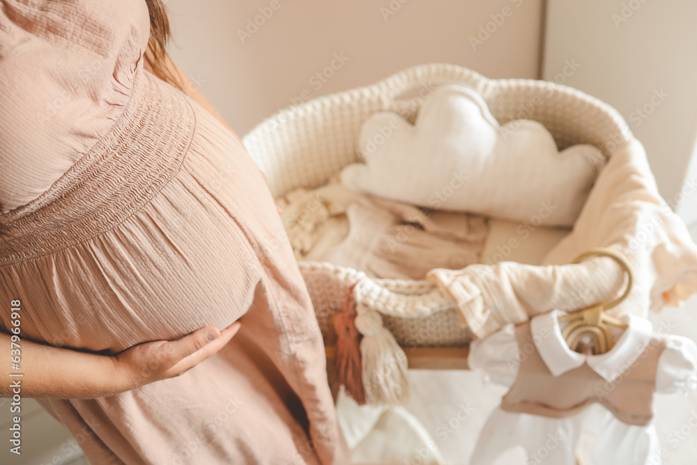 Pregnant woman waiting for a baby in the nursery near the cradle