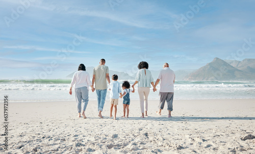 Family, holding hands and walking outdoor on a beach with love, care and happiness on summer vacation. Behind, space in sky or travel with men, women and children together for holiday adventure