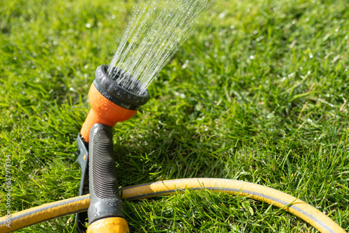 Shallow focus of an selectable generic garden sprinkler head seen showing a lush lawn during summer.