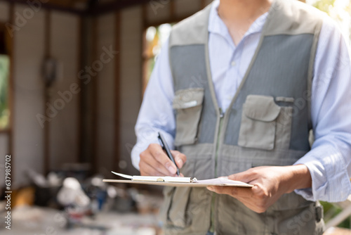 inspector or engineer is inspecting construction and quality assurance new house using a checklist. Engineers or architects or contactor work to build the house before handing it over to the homeowner