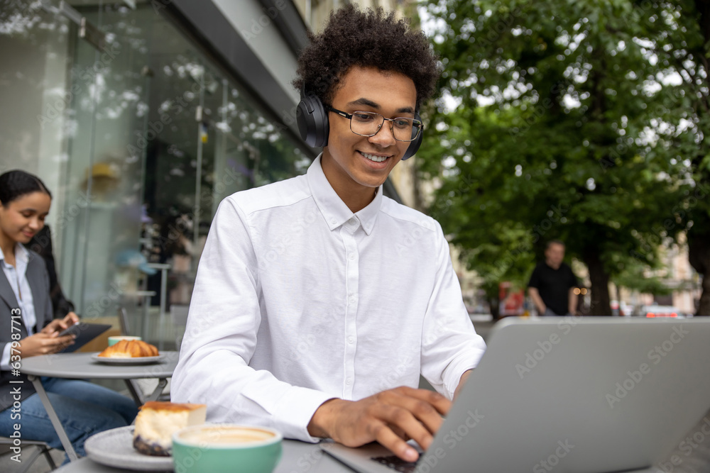Young businessman with headphones working remotely and looking contented