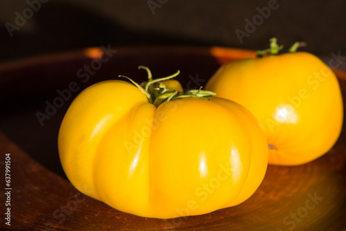 Yellow tomatoes on a wooden plate, close-up, selective focus