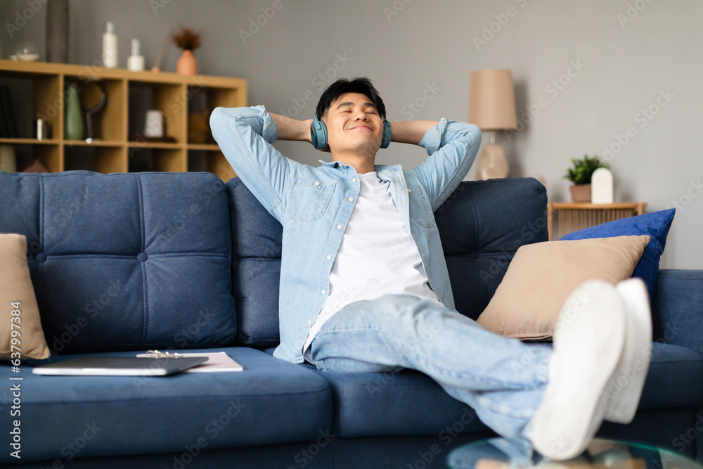 Japanese man relaxing with wireless headphones listening to music indoor