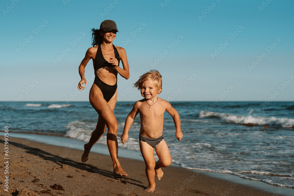 beautiful sports mom runs with her son along the seashore on the beach