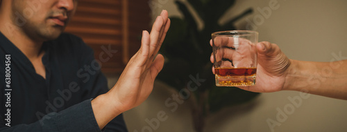 Fotografie Alcoholism, sad depressed asian young man refuse, push alcoholic beverage glass, drink whiskey, sitting alone at night