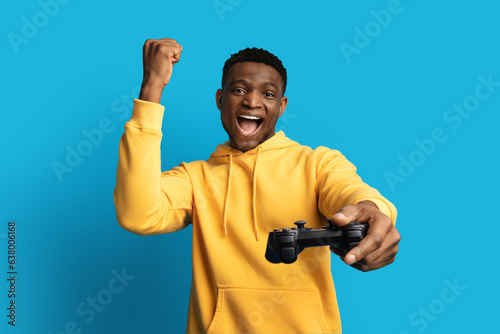 Thrilled black guy gamer with joystick playing video game