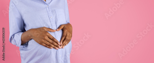 Young black pregnant woman puts heart shape hands on big belly