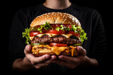 Person's hands grasp a delectable burger, loaded with juicy layers and a medley of fresh toppings, tempting every sense