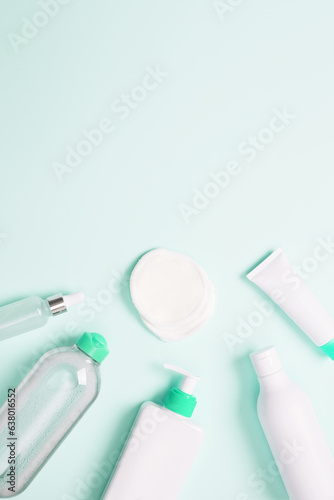 Cosmetic beauty products on green background. Bottles and tubes with branding mock up. Skin care and beauty concept. Top view, flat lay, copy space