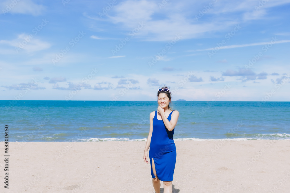 Happy and cheerful asian woman in blue dress on the sunny beach of Thailand.