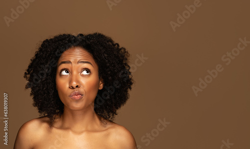 Confused beautiful half-naked millennial black woman looking at copy space