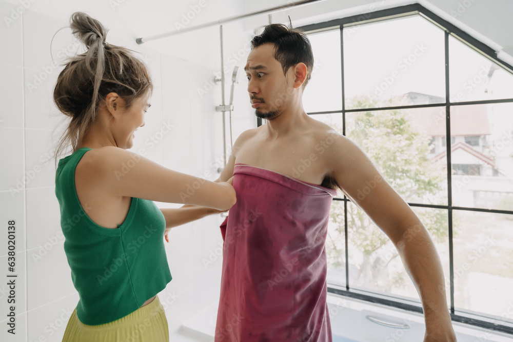 Fototapeta premium Funny and playful asian couple, wife helping husband after taking bath.