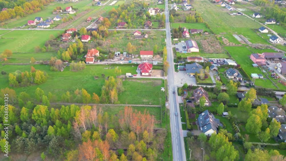 Aerial straight flight over traffic on main street of small town. Cars drive on street separating small shops and houses. Beautiful summer day.