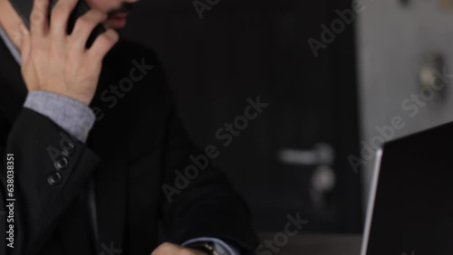 Businessman working in the office talking on the phone and having a laptop in front of him
