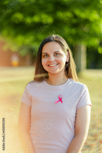 Happy confident middle aged woman with pink ribbon on t shirt looking at camera