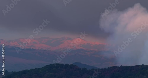 Loma Fire wildfire burning in Santa Cruz Mountains above San Jose with smoke plume at sunset with mountains in distance