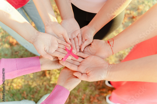 Closeup of women hands holding pink ribbon standing on the street