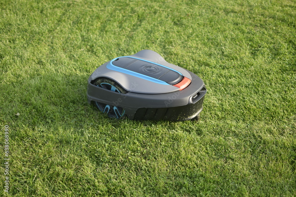 The lawnmower robot mows the grass in the garden. The lawnmower robot mows the grass in the garden.