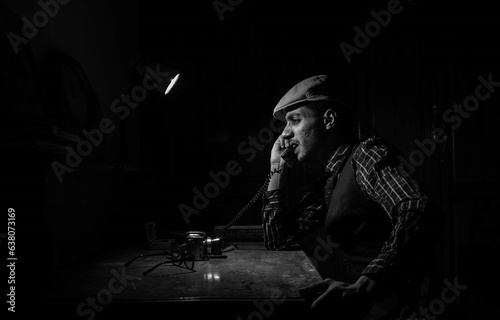 Vintage Black and White Portrait of a Man in the 1940s Speaking on the phone. Retro portrait from the 20th century. Man dressed peaky blinders style. Portraits from the 20th century.