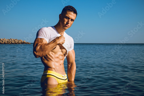 Portrait of a muscle handsome young man with stylish haircut in a wet T-shirt.posing in the sea