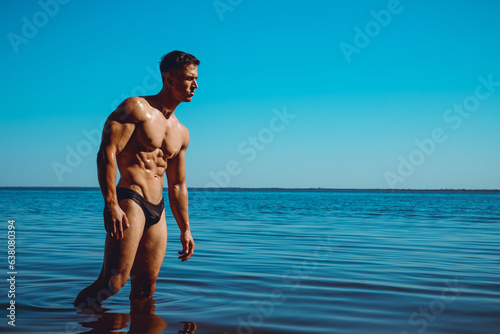 Portrait of a muscle handsome young man in balck swimwear posing in the sea