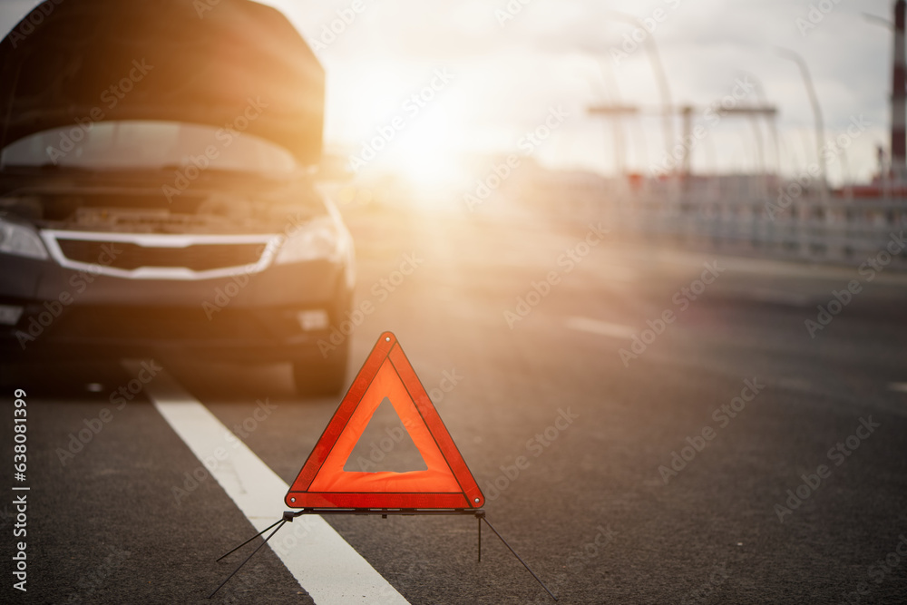 Red emergency stop sign on road. Blurred broken down car with warning