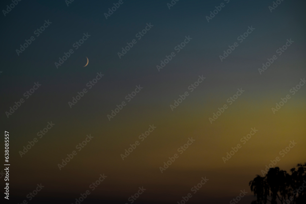 Moon in middle of summer after color sunset on dark sky Moon in middle of summer after color sunset on dark sky