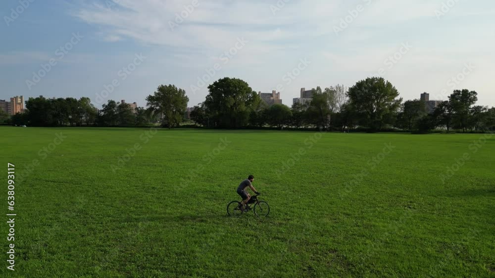 man riding mountain bike a grass field (public city park with trees) on sunny day (filmed from above, drone footage, birds eye view shot) looking down, casual clothes, summer exercise biking, cycling man riding mountain bike a grass field (public city park with trees) on sunny day (filmed from above, drone footage, birds eye view shot) looking down, casual clothes, summer exercise biking, cycling