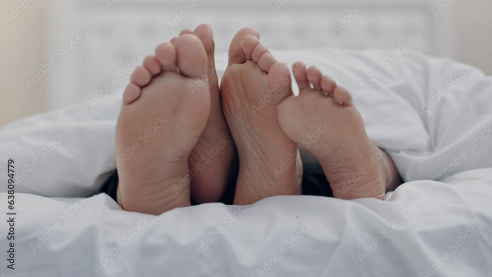 Feet, couple and rubbing in bedroom in home, relax in peace or rest in blanket in the morning together. Barefoot, bed and man and woman sleeping in comfort, bonding to play and care for love in house Feet, couple and rubbing in bedroom in home, relax in peace or rest in blanket in the morning together. Barefoot, bed and man and woman sleeping in comfort, bonding to play and care for love in house