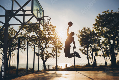 black man doing sports, playing basketball on sunrise, jumping silhouette © mary_markevich