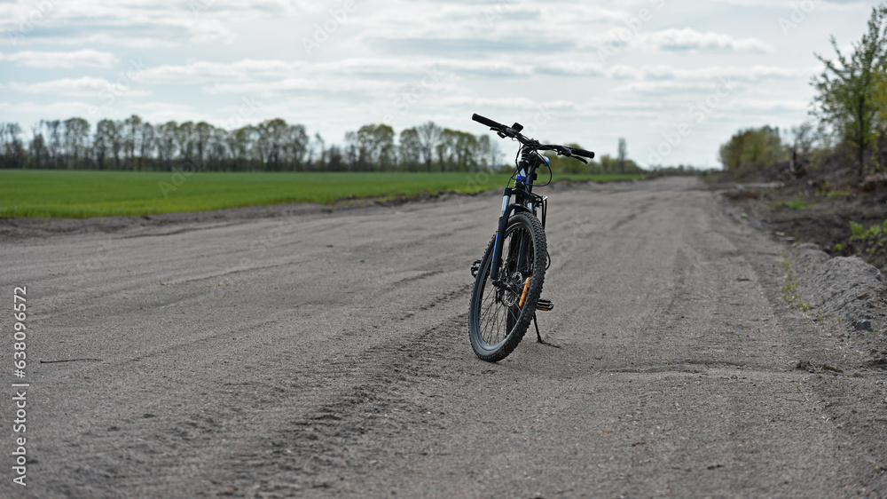 Obraz premium Mountain bike. stands on a field road. spring or autumn. concept of cycling, repair or breakage, sports, outdoor activities. bike on trail, front wheel in focus. healthy lifestyle