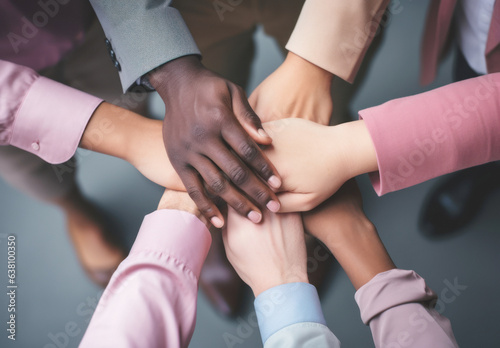 A diverse group of multiracial coworkers join their hands in the center, overlapping them as a sign of unity, teamwork, diversity and workplace cooperation,startup and collaboration business concept