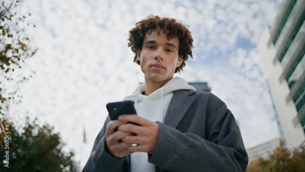 Young man using phone outdoors portrait. Earphones teenager listening music Young man using phone outdoors portrait. Earphones teenager listening music