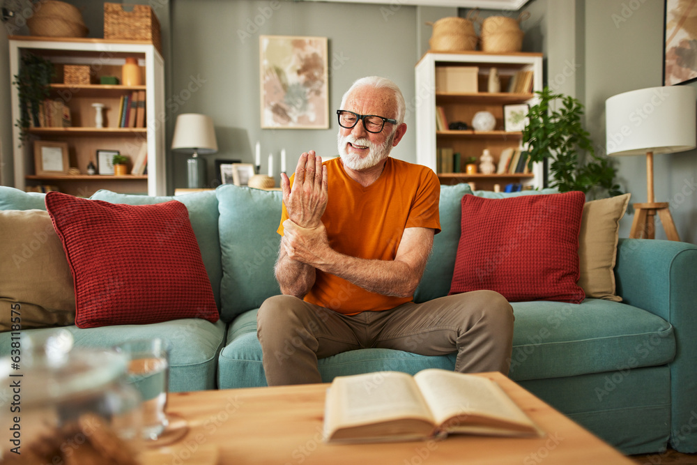 Elderly man suffering from his wrist joint pain at home Elderly man suffering from his wrist joint pain at home